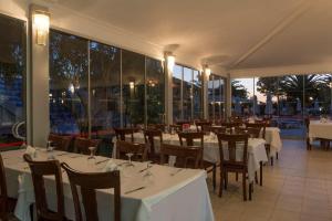 a restaurant with white tables and chairs and windows at Le Monde Beach Resort & Spa in İzmir