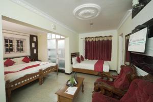 a hotel room with two beds and a tv at Ganga's Sri Balaji Cottage in Ooty