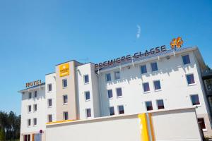 a white building with a sign on top of it at Première Classe Roissy - Aéroport CDG - Le Mesnil-Amelot in Le Mesnil-Amelot