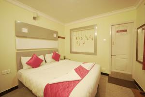 1 dormitorio con 1 cama blanca grande con almohadas rojas en Ganga's Sri Balaji Cottage, en Ooty