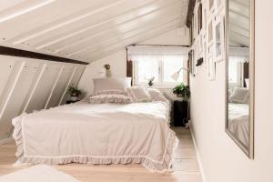 Schlafzimmer mit einem weißen Bett und einem Spiegel in der Unterkunft ForRest unikt designat hus mitt i skogen in Alfta