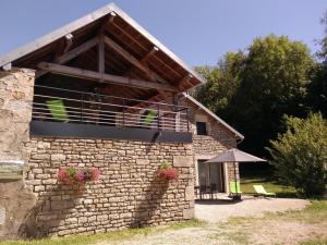 Edificio de piedra con balcón y patio en Gite le Nid du Poupet, 