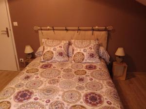 a bed with pillows and a comforter and two lamps at Gite le Nid du Poupet in Ivrey