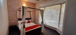 a bedroom with a canopy bed and a window at amravati resort in Solan