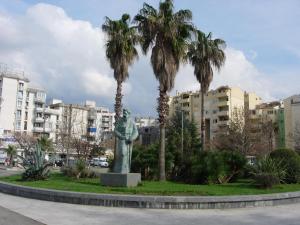 a statue of a woman in a park with palm trees at Rooms & Apartments Anka in Bar