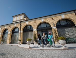 Tres mujeres montando bicicletas delante de un edificio en Residence Cà Beregana, en Vicenza