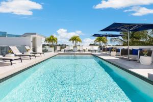 uma piscina com cadeiras e guarda-sóis num edifício em H2O Suites- Adults Only em Key West