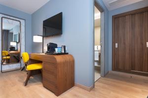 a room with a desk with a television and a yellow chair at Hotel Lima - Adults Recommended in Marbella
