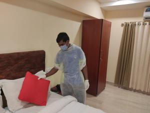 Ein Mann in einem Zimmer, der ein Kissen auf ein Bett legt. in der Unterkunft Hotel Green Plaza in Thrissur