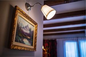 a picture hanging on a wall with a lamp at Trattoria Al Gallo in Bran