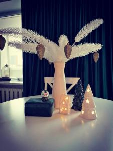 un jarrón blanco con plumas y adornos de Navidad en una mesa en Cosy center Apartment, en Klaipėda