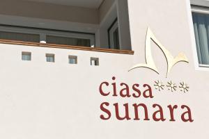 una señal en el lado de un edificio con un logotipo de clasena sierra en Ciasa Sunara, en Colfosco