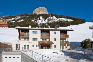 a hotel in the snow with a mountain in the background at Ciasa Sunara in Colfosco