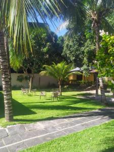 einen Park mit Palmen, Tischen und Stühlen in der Unterkunft Pousada Lele do Pero in Cabo Frio