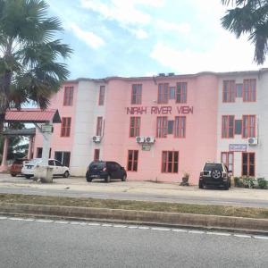 ein rosafarbenes Gebäude mit davor geparkt in der Unterkunft Nipah River View Bajet Hotel in Kuala Terengganu