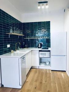 Una cocina con electrodomésticos blancos y azulejos azules. en Apartament z Widokiem na Morze, en Gdansk