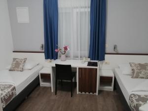 a room with two beds and a desk and a table at Hotel Dina in Međugorje