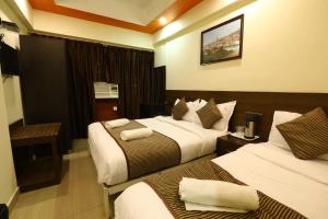 a hotel room with two beds and a table at Hotel Sona in Panaji