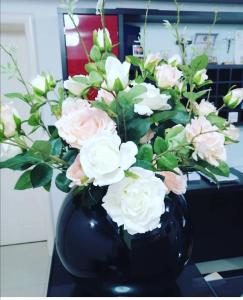 un jarrón negro lleno de flores rosas y blancas en Hotel Dina, en Međugorje