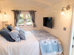 a bedroom with a bed and a tv on the wall at Yew Tree View Luxury Shepherd's Hut in Sturminster Newton
