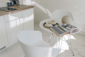 biały stół i krzesła z książką i filiżankami kawy w obiekcie Centro Design Apartments - Półwiejska w Poznaniu