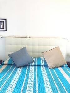 uma cama com lençóis e almofadas azuis e brancos em Domus Afrodite em Anzio