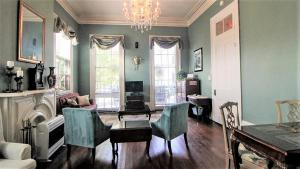 uma sala de estar com um lustre e uma mesa e cadeiras em The Mansion on Royal em Nova Orleães