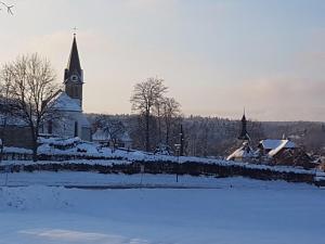 a church with a clock tower in the snow at Haus Seeliger im Fichtelgebirge in Brand