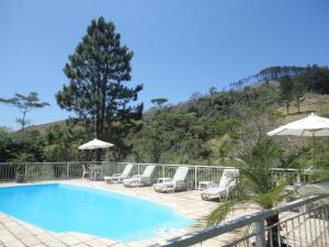 a swimming pool with chairs and umbrellas on a balcony at Hotel Pousada Esmeralda in Itatiaia