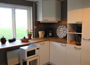 eine Küche mit weißen Schränken und einer Mikrowelle auf der Theke in der Unterkunft Brösarps Norra Backar in Brösarp