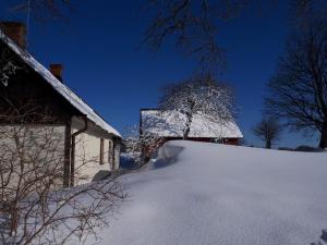 ein schneebedecktes Haus neben einem Gebäude in der Unterkunft Brösarps Norra Backar in Brösarp