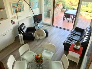 een woonkamer met een glazen tafel en witte stoelen bij Panoramic Apartment Poggettone Air conditioned in Punta Ala