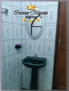 a bathroom with a sink and a sign on the wall at Hostal Corona Blanca in Sucre