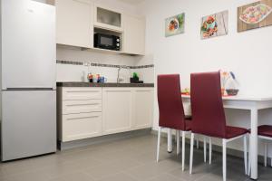 a kitchen with white cabinets and a white table and chairs at Ca' Corazzeri in Venice