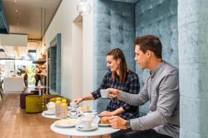 a man and woman sitting at a table eating food at Motel Keckeis Inn - Self Check-in in Sulz