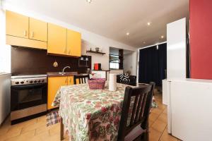 uma cozinha com uma mesa e uma cozinha com armários amarelos em One bedroom appartement at Catania 200 m away from the beach with furnished terrace and wifi em Catânia