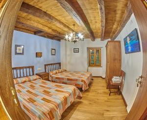 a bedroom with two beds and a chandelier at Casa Rural Lenco in Cilveti