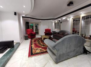 a living room with a gray couch and red chairs at Luxury Apartments in Cairo