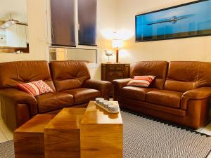 Sala de estar con 2 sofás de cuero marrón y mesa de centro en Gîte Loirizon vue Loire 4 personnes, en Ingrandes