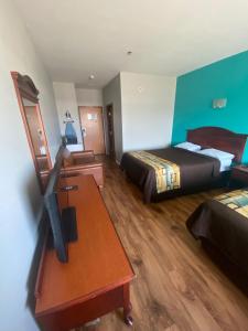 Habitación de hotel con 2 camas y escritorio con TV. en Tropicana Inn and Suites en Dallas