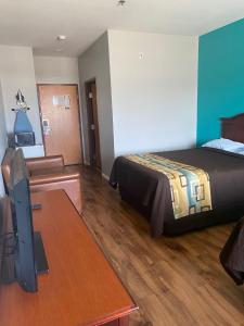 Habitación de hotel con cama, escritorio y TV. en Tropicana Inn and Suites en Dallas