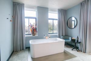 La salle de bains est pourvue d'une baignoire blanche et d'un miroir. dans l'établissement Hotel Marktstad, à Schagen