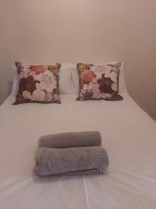 uma cama branca com duas almofadas e um tapete em Dagbreek em Beaufort West