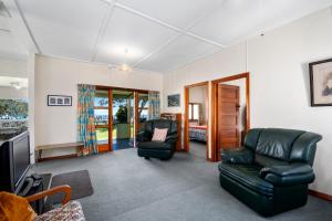 圖朗伊的住宿－Marina Views - Motuoapa Bach，客厅配有两把椅子和电视