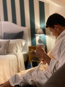 mężczyzna siedzący w łóżku czytający książkę w obiekcie Palazzina300 w mieście Treviso
