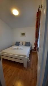 białe łóżko w pokoju z drewnianą podłogą w obiekcie Apartments Grbin w mieście Ližnjan