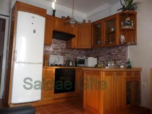 a kitchen with wooden cabinets and a white refrigerator at Saldae Gîte Appartement in Bejaïa