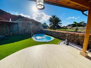 a backyard with a swimming pool and a stone wall at Villa Bravo in Anfi Tauro Golf resort in Mogán