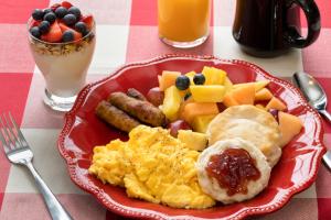 un plato rojo de desayuno con huevos, salchichas y fruta en Country Inn at Camden Rockport en Rockport