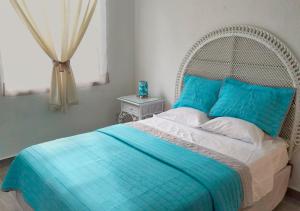a bedroom with a bed with blue sheets and a window at Departamento Tucán in Cancún